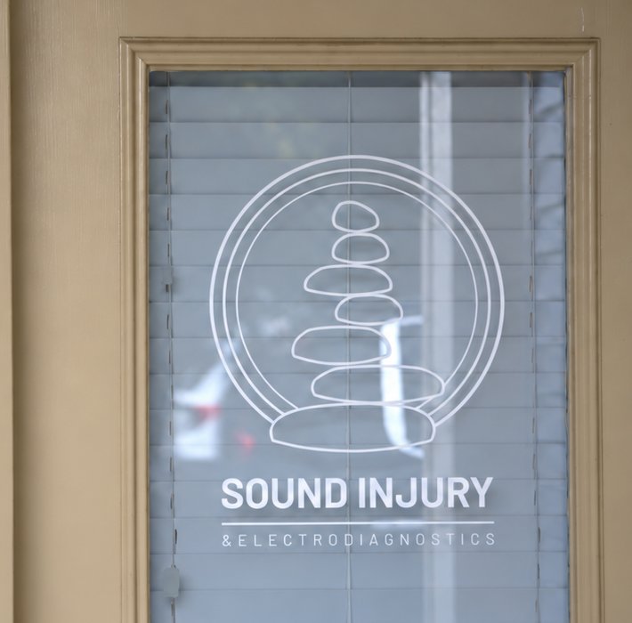 The Sound Injury cairn logo etched on the glass of the clinic door in Edmonds